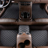 Interior view of a car with dark brown quilted floor mats and leather seating.