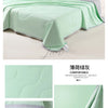 Light green ice silk cooling blanket draped over a bed, showing its quilted texture and soft fabric.