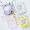Three cute photo albums with heart cutouts in purple, pink, and yellow, each with a string for hanging.