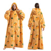 A woman models an oversized orange sherbet colored wearable blanket hoodie with a hood and long sleeves.