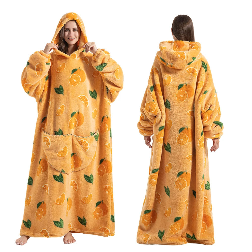 A woman models an oversized orange sherbet colored wearable blanket hoodie with a hood and long sleeves.