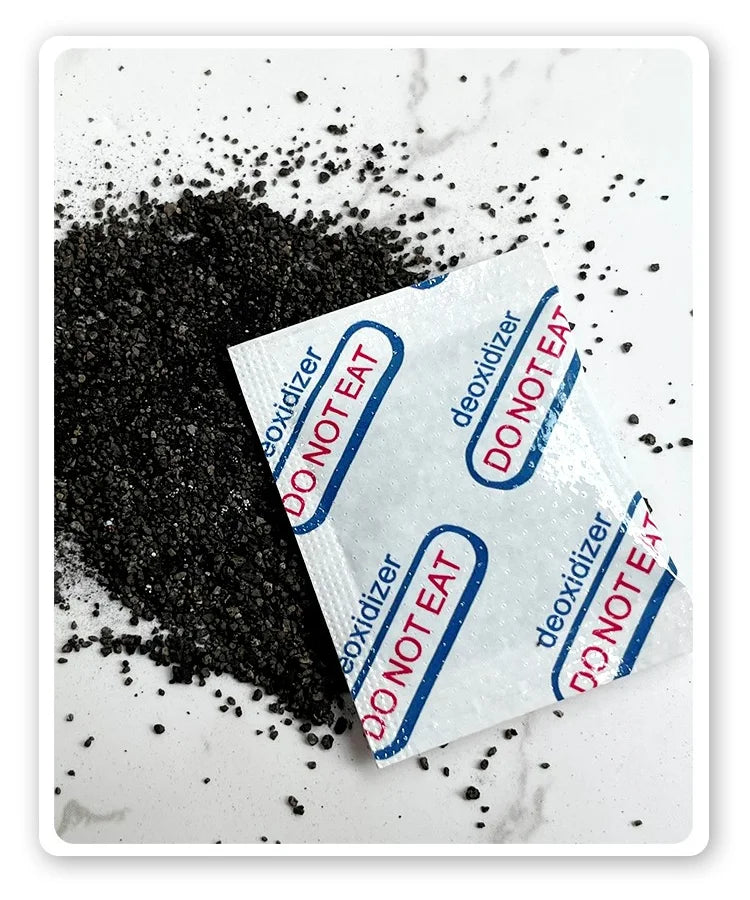 A pile of black food grade oxygen absorbers next to a white packet labeled DO NOT EAT and DEOXIDIZER.