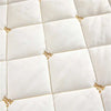 White quilted bed skirt with gold embroidery on a diamond pattern.