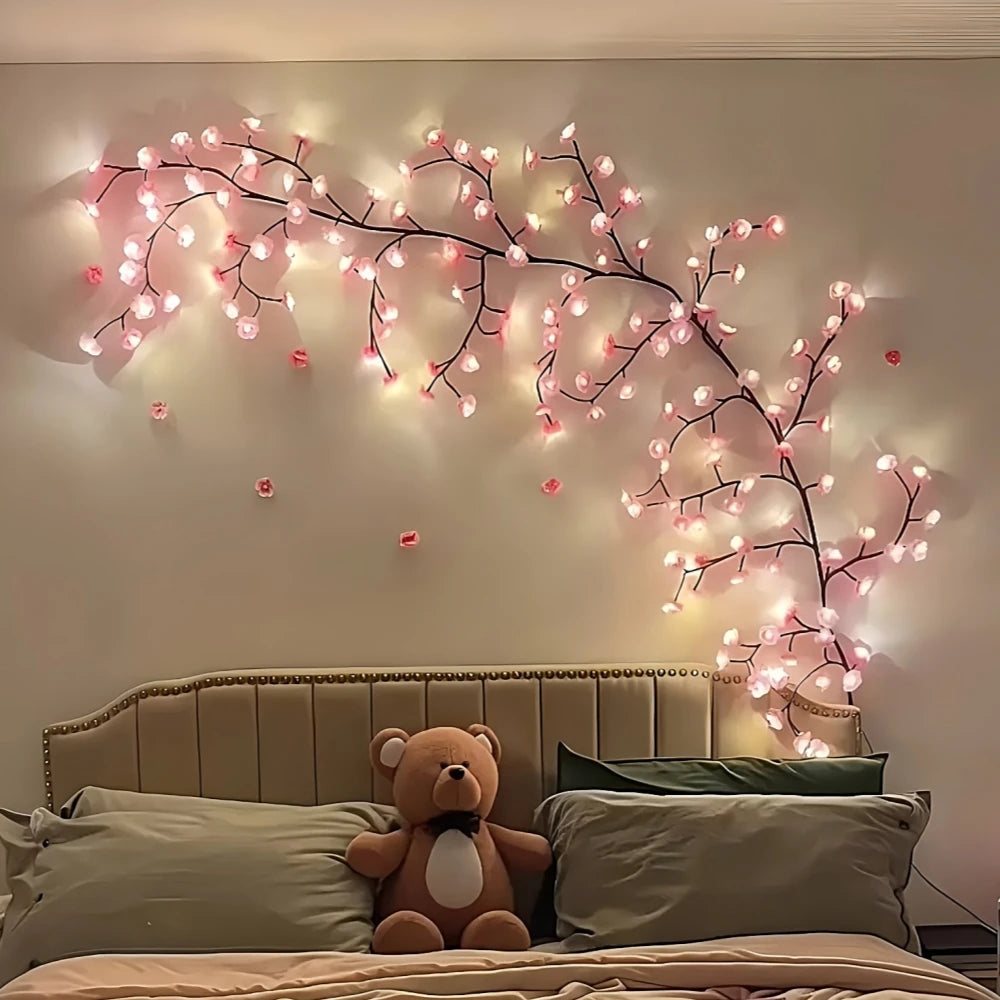 A decorative cherry blossom tree lamp with pink LED lights mounted on a wall above a bed.
