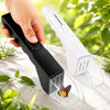 A hand holds a black handheld insect catcher with a butterfly design, next to its clear plastic container.
