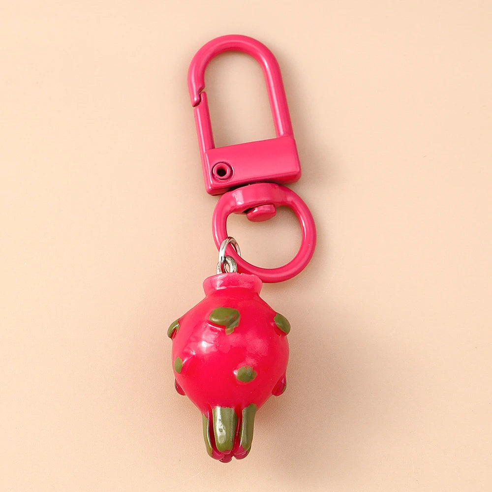 Helles rosa Harz-Erdbeerkeychain mit grünem Stiel und Blättern an einer rosa Metallverschluss