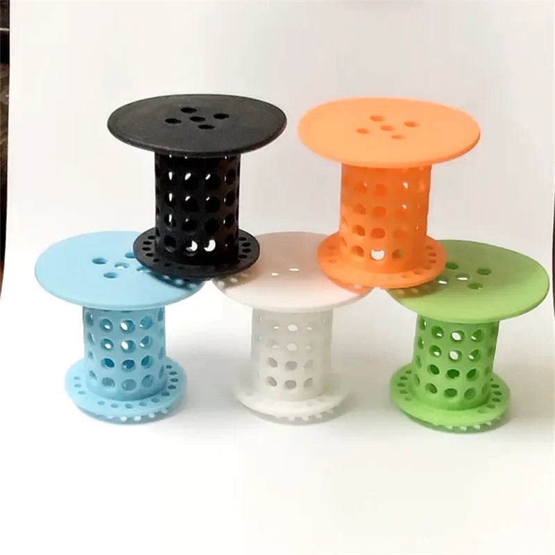 A collection of colorful flexible hair catcher drain covers in various shades including black, orange, light pink, and green.