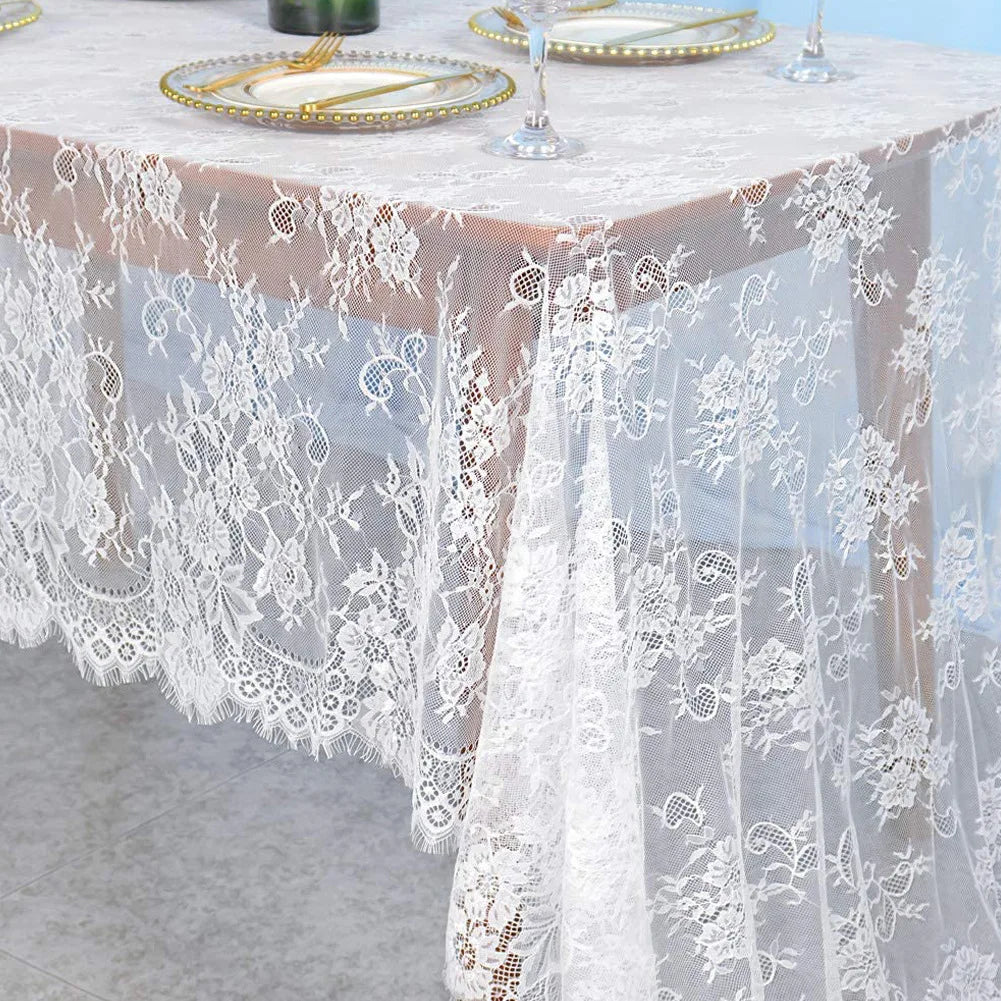 Vintage white embroidered floral lace table runner draped over a light pink tablecloth.