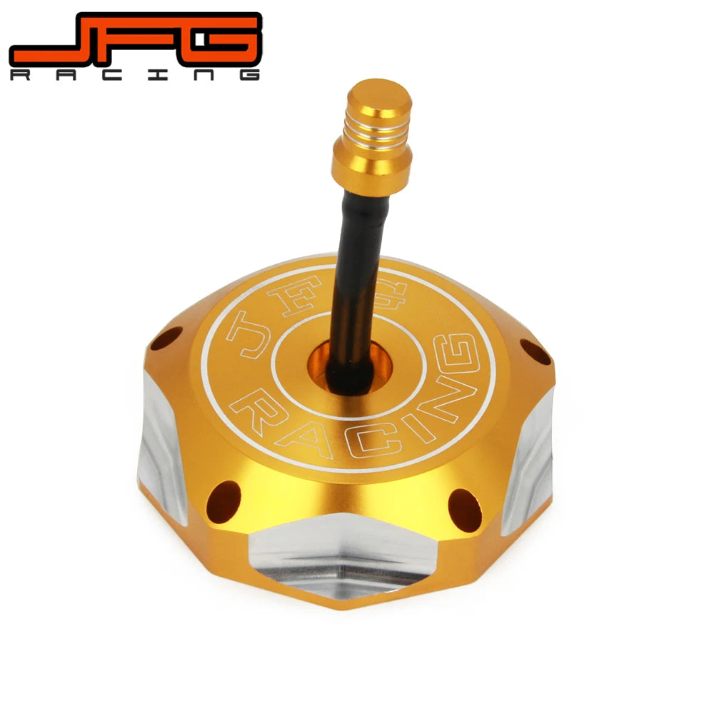 A gold-colored aluminum motorcycle fuel tank cap with a black threaded fitting and an engraved logo.