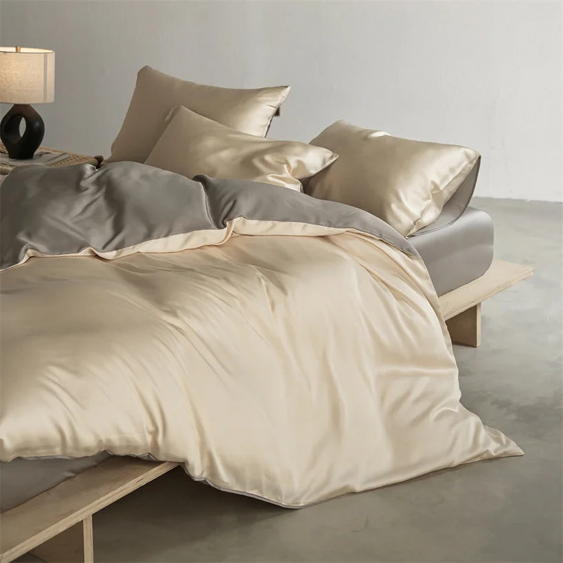 A luxurious beige mulberry silk duvet cover set displayed on a bed with neutral bedding and a bedside lamp.