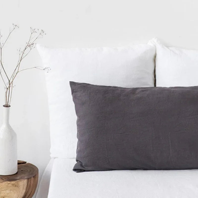 A gray linen pillowcase is displayed on a white surface with a white pillow in the background.