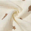 Close-up of a cream-colored fabric with small brown sun and dust motifs, showing the soft texture and drape.