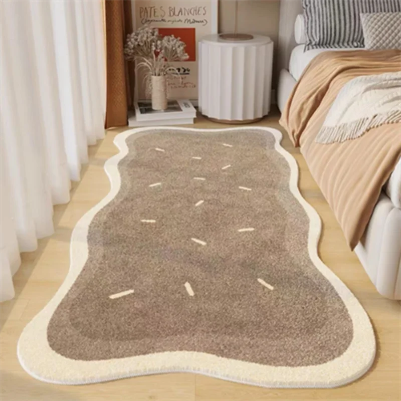 A rectangular beige area rug with light brown accents and a white border placed on a light wood floor.