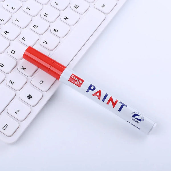A red paint marker is placed diagonally across a white computer keyboard.