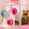 A pink silicone suction cup toy with multiple colored discs is shown against a blurred background.