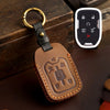 A brown leather key fob case with a brass ring attached, next to a white electronic key fob.