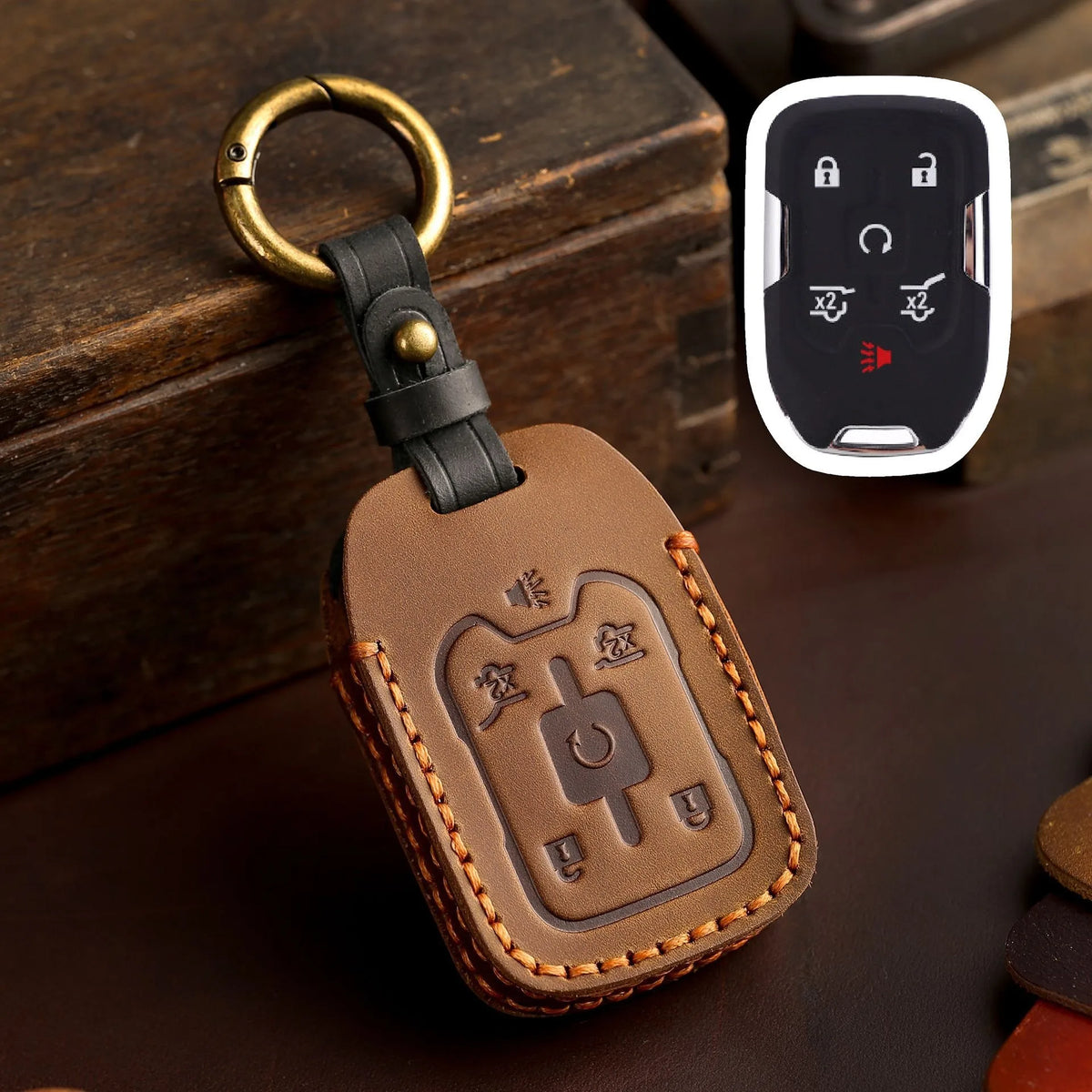 A brown leather key fob case with a brass ring attached, next to a white electronic key fob.