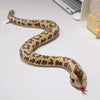 A brown patterned snake plush toy, resembling an anaconda, is coiled on a white surface.
