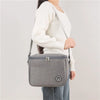 A woman is holding a gray thermal insulated lunch bag with an adjustable shoulder strap.