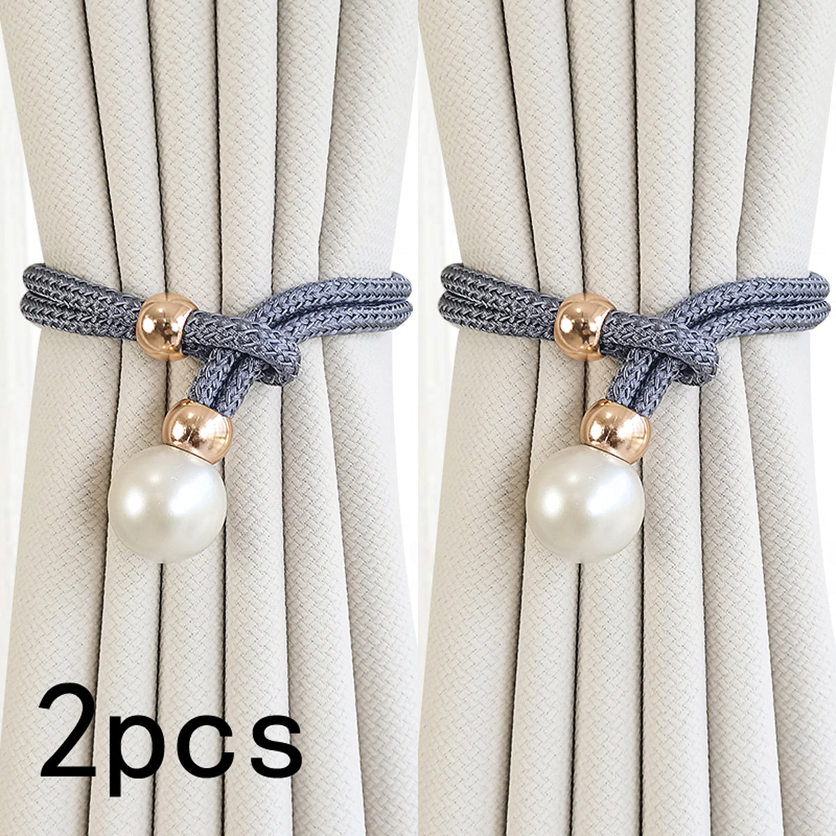 A set of two pearl and rope curtain tie-backs with gold accents against a light beige curtain.