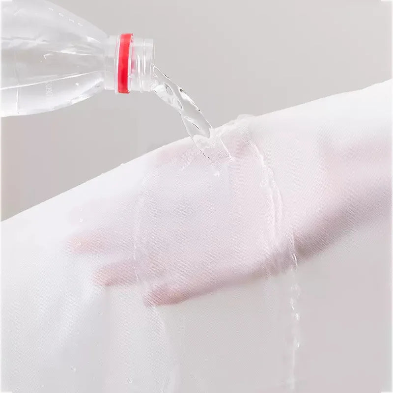A clear bottle is pouring liquid onto a white fabric, demonstrating the transparent zippered garment bag for clothes storage.