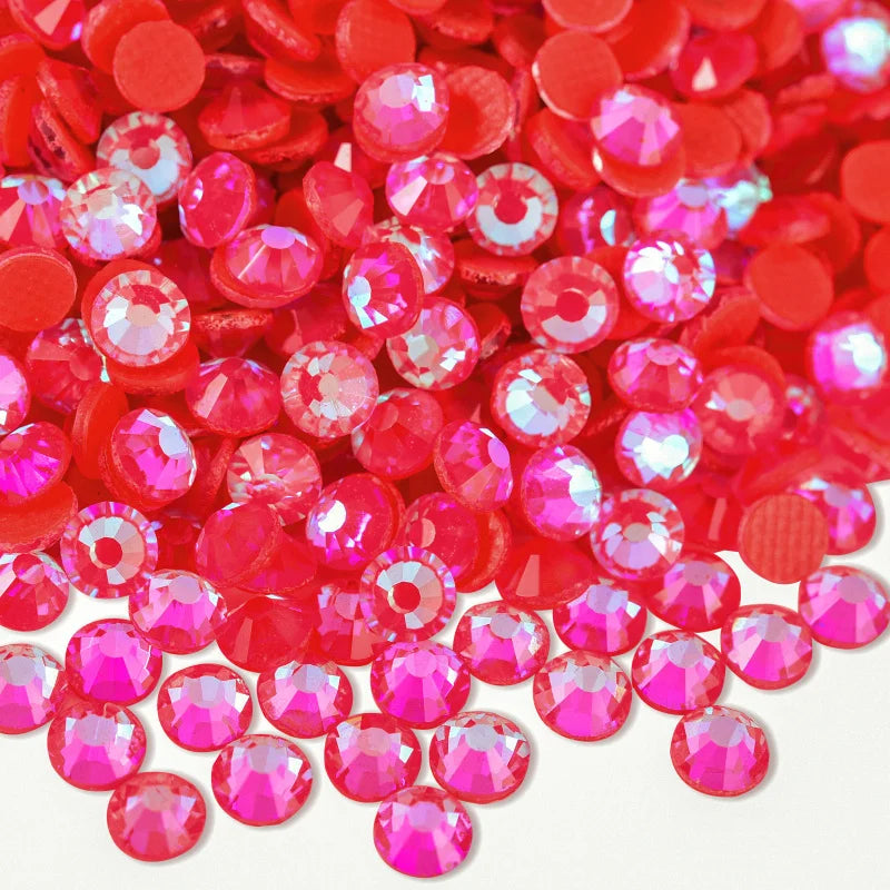 A close-up view of numerous small, round, faceted red and pink rhinestones scattered on a white surface.