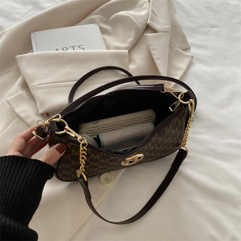 A dark brown PU leather crossbody bag with gold accents resting on a white sheet.