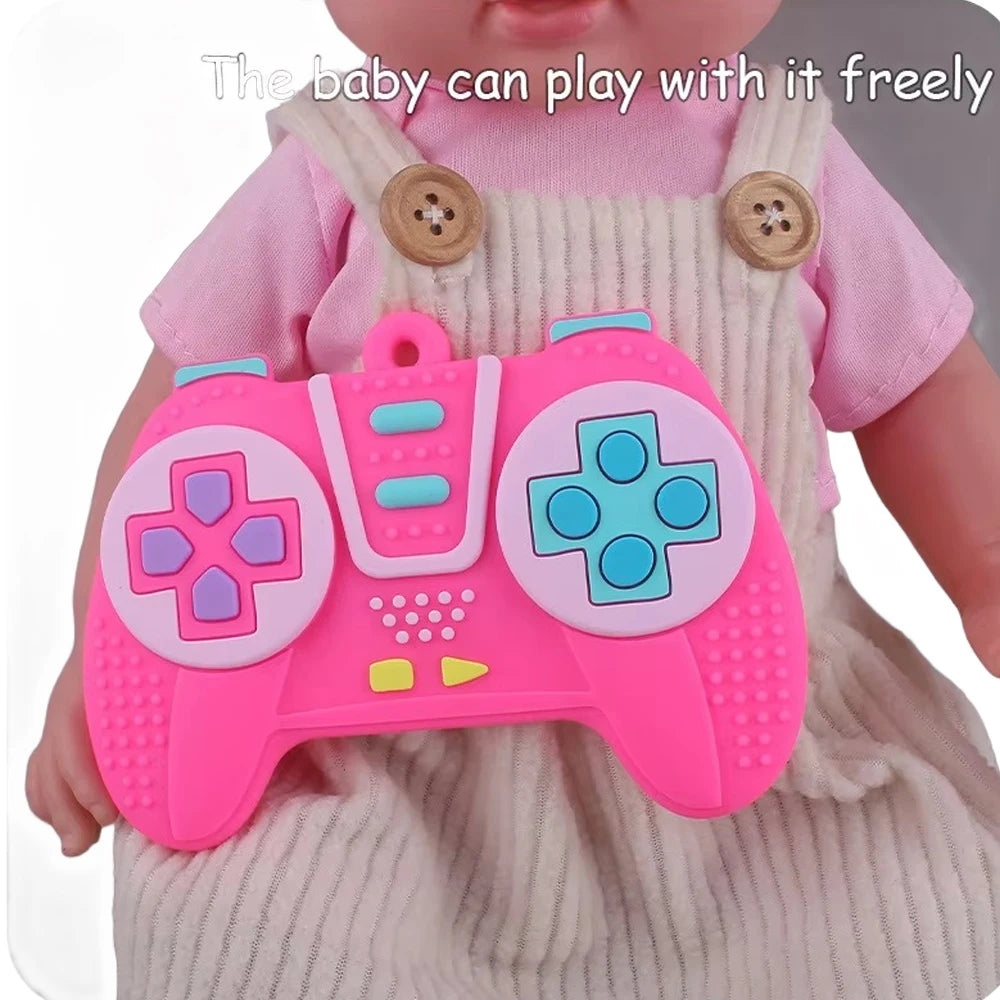 A pink silicone game controller toy is being held by a baby wearing a light pink dress.
