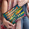 A hand holds a vintage sardine print canvas cosmetic bag against a pink patterned fabric.