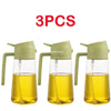 Three glass oil spray bottles with green caps and yellow oil inside