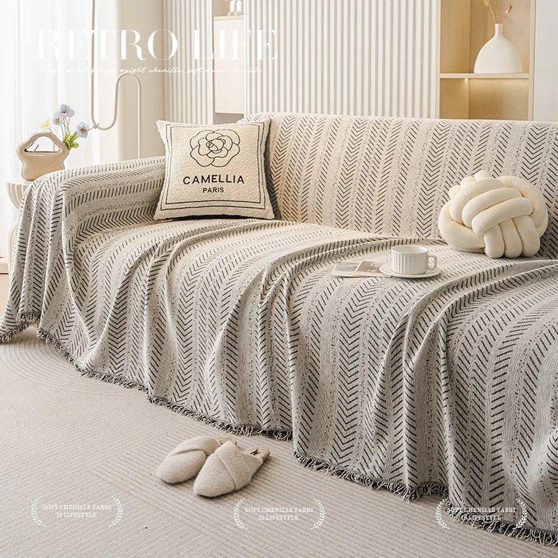 Elegente Fischgrätenmuster-Sofa-Abdeckung in Beige- und Grautönen, drapiert auf einem hellen Sofa.