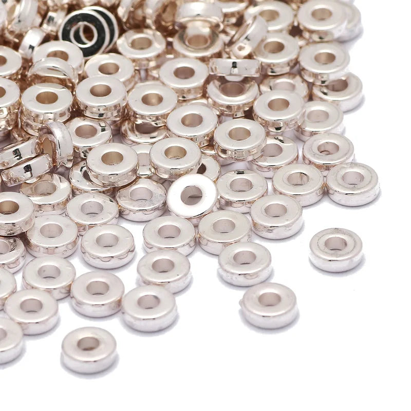 A pile of small, round silver-colored acrylic spacer beads for jewelry making.