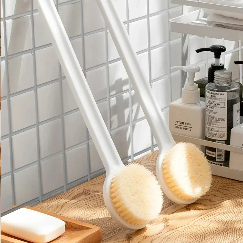 Cepillo ergonómico blanco de mango largo con cabeza de cerdas redonda, mostrado sobre una superficie de madera.