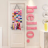 A pink hair bow and clip organizer with rope hangers displayed on a white door and wall.