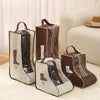 Brown and gray storage bags for tall boots with handles, displayed on a light rug next to a sofa.