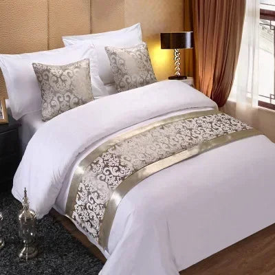 White bed with a decorative beige knit runner cover and light gold accents in a bedroom setting
