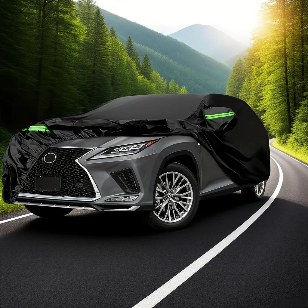 A black all-weather car cover is placed on a dark road, with a modern SUV or sedan visible in the background.