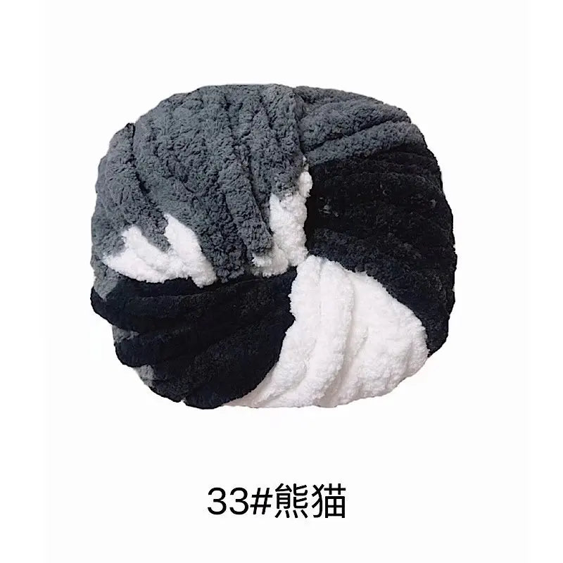 A ball of chunky gray, black, and white acrylic yarn for knitting and crochet.