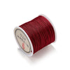 A spool of deep red nylon macramé cord for jewelry making is shown on a white background.