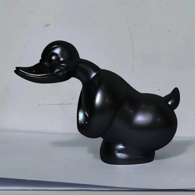A glossy black resin duck hood ornament for a car or motorcycle.