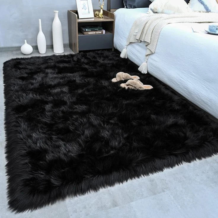 A luxurious black velvet plush carpet placed on a light gray floor next to a white bed and decorative items.