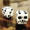 A set of white gothic skull dice resting on a dark wooden surface.