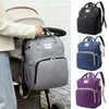 A collection of gray and blue diaper bags and backpacks displayed next to a person holding one.