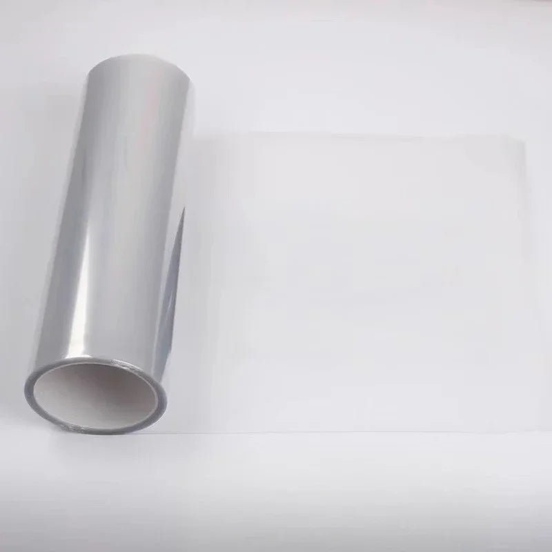 A roll of smoke black headlight and taillight tint film lying on a white surface.