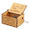 A hand-cranked wooden music box carved in the shape of a box, featuring a lid with the text You Are My Sunshine.