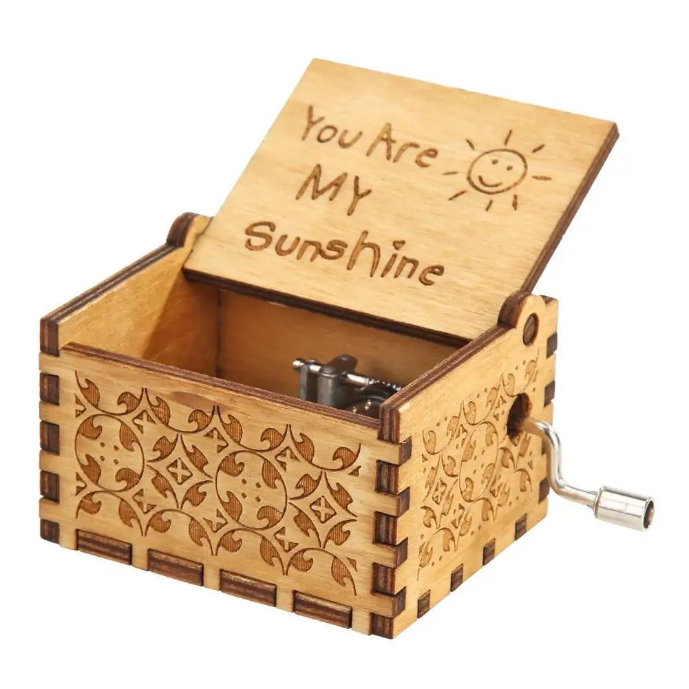 A hand-cranked wooden music box carved in the shape of a box, featuring a lid with the text You Are My Sunshine.