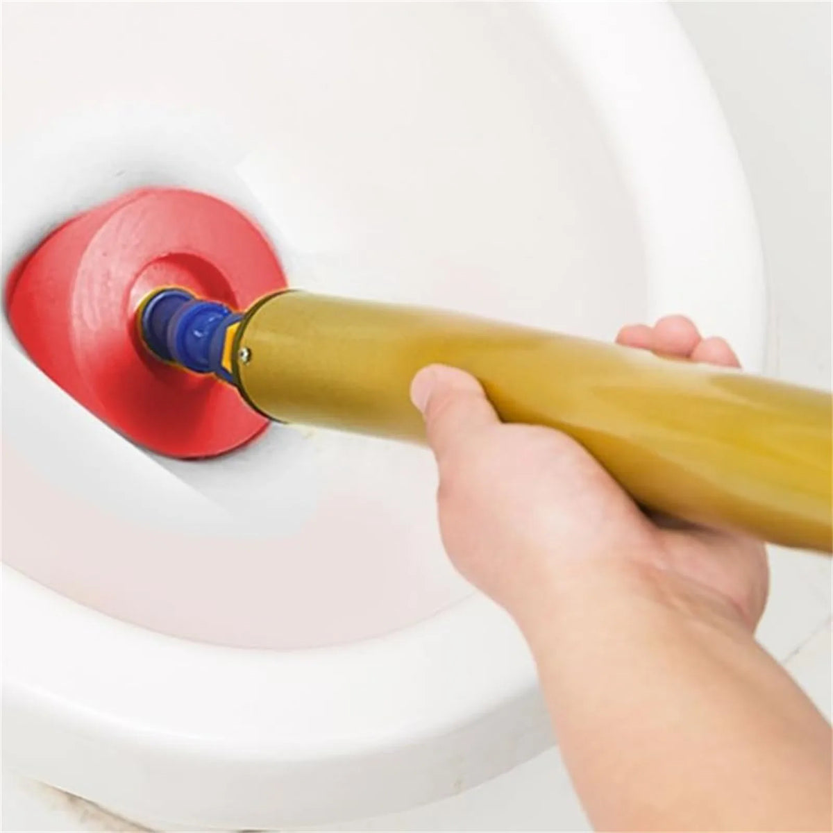 A hand is using a yellow high-pressure toilet plunger with a blue pump to clear a clog in a white toilet bowl.