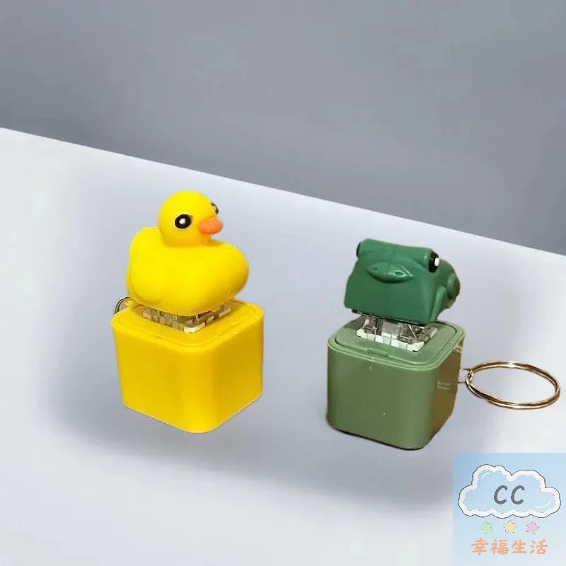 A yellow duck-shaped fidget keychain with an LED light and sound mechanism, packaged in a yellow plastic holder.