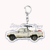 A silver metal key ring attached to a miniature off-road truck model.