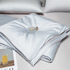 Light blue ice silk quilt folded on a bed with a brass zipper detail.